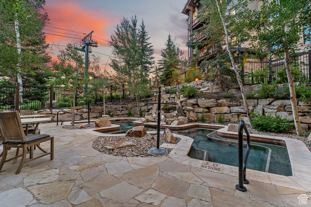 Pool at dusk featuring a patio area