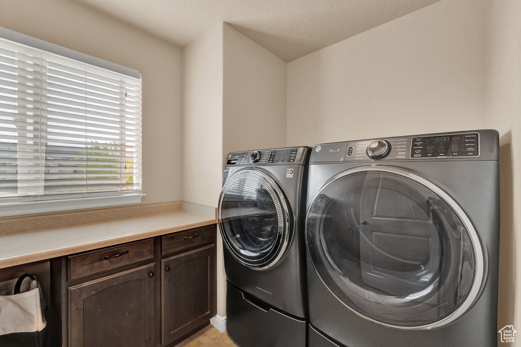 Laundry room with cabinets, washing machine and clothes dryer, and light tile patterned floors