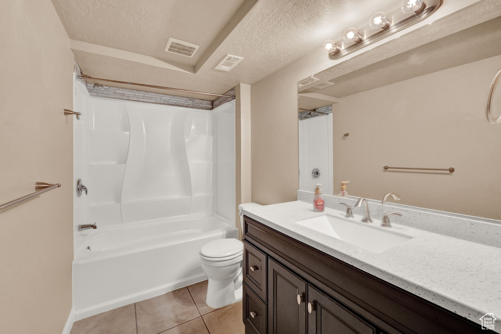 Full bathroom with vanity, shower / tub combination, toilet, a textured ceiling, and tile patterned flooring