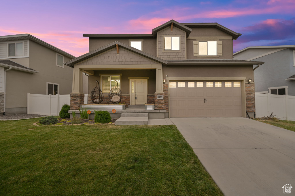 View of front of house with a porch, a garage, and a lawn