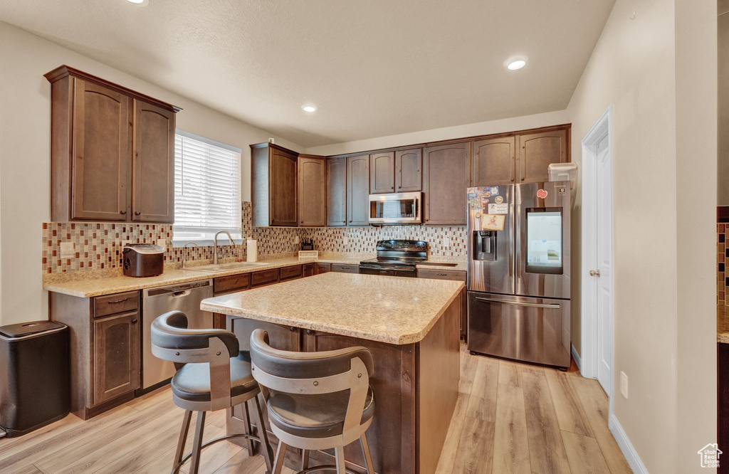 Kitchen featuring stainless steel appliances, light hardwood / wood-style floors, and a center island