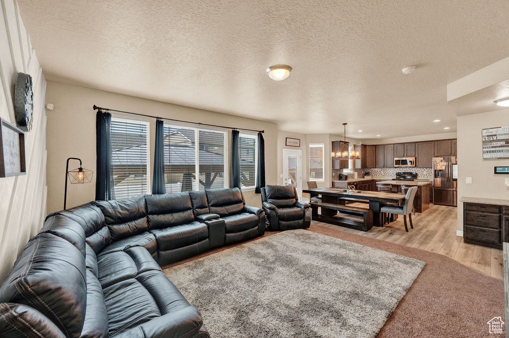 Living room with a textured ceiling, light hardwood / wood-style flooring, and an inviting chandelier