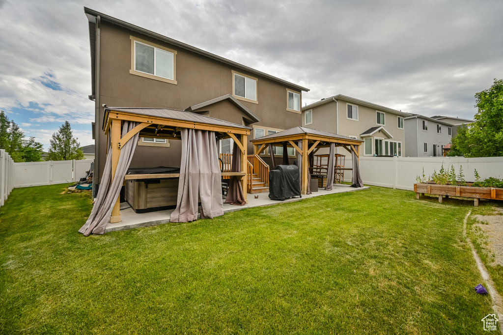 Back of house with a patio area, a gazebo, a lawn, and a hot tub