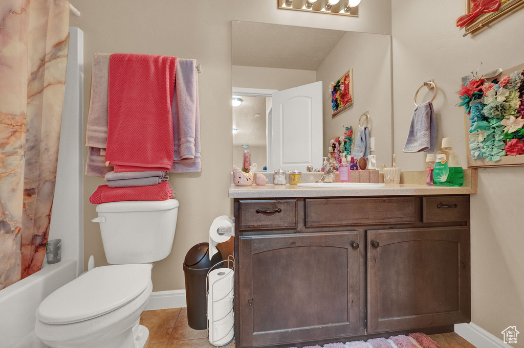 Full bathroom with tile patterned floors, vanity, shower / bath combo, and toilet