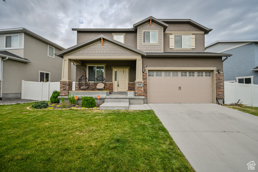 Craftsman inspired home featuring a porch, a garage, and a front lawn