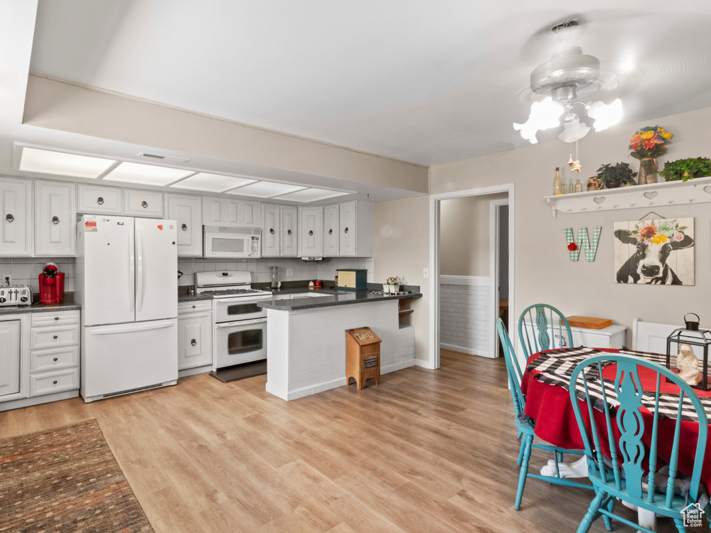 Kitchen with light hardwood / wood-style flooring, white cabinets, backsplash, and white appliances