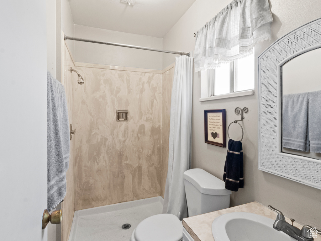 Bathroom with vanity, a shower with shower curtain, and toilet