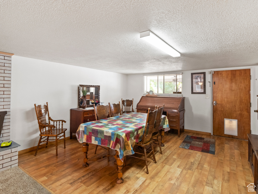 Dining room featuring light hardwood / wood-style floors, a textured ceiling, and brick wall