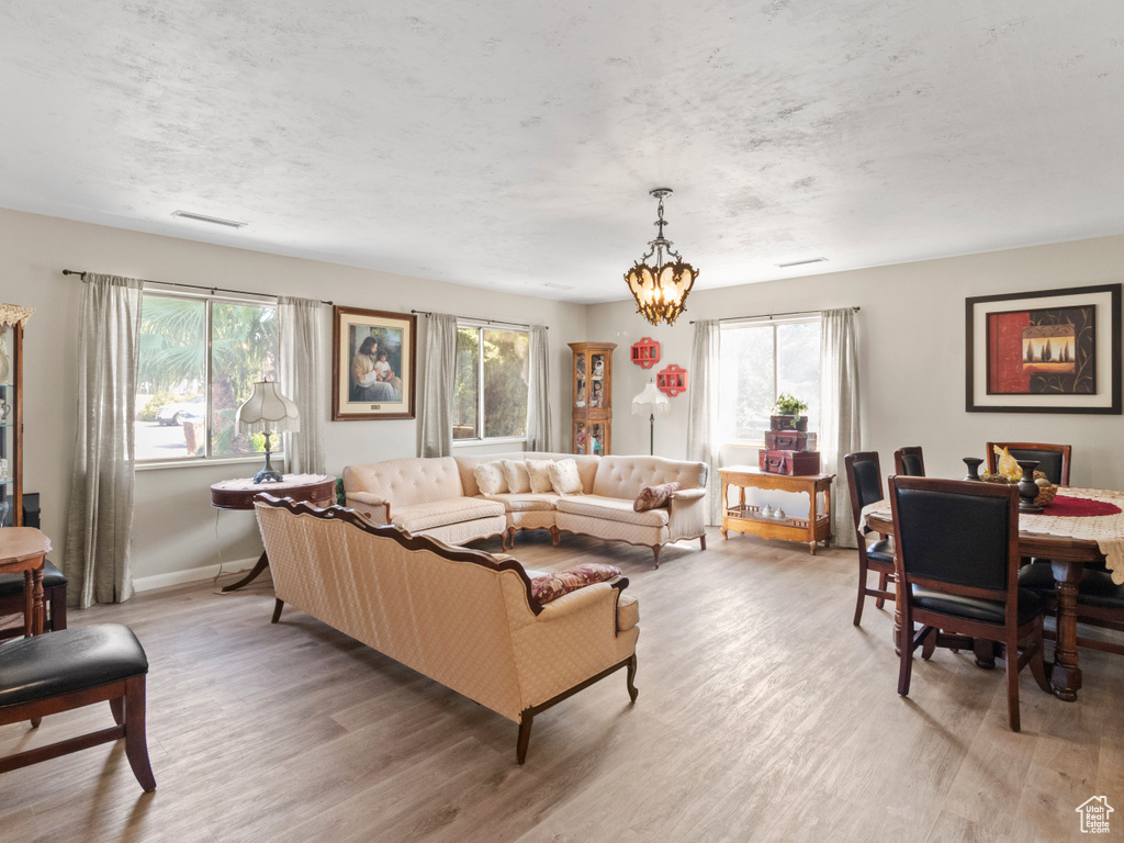 Living room with an inviting chandelier, wood-type flooring, and a wealth of natural light