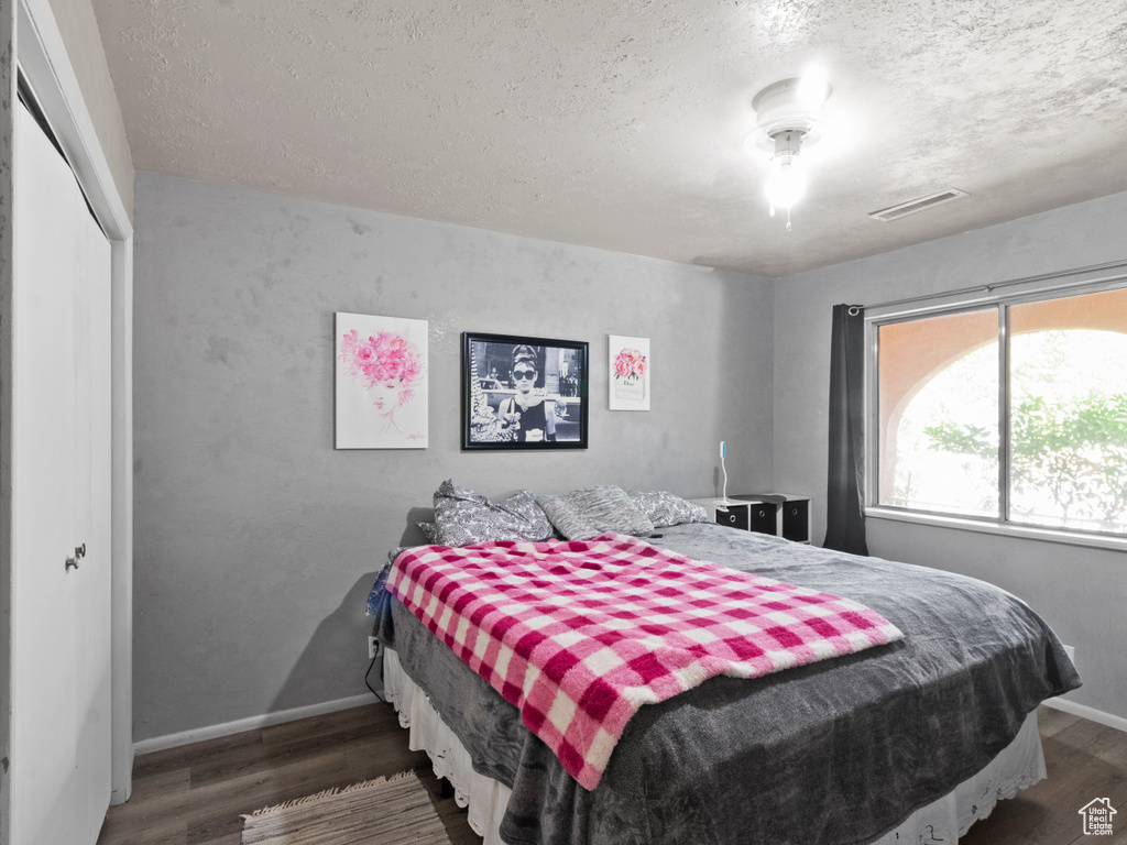 Bedroom with dark hardwood / wood-style flooring, a closet, and a textured ceiling