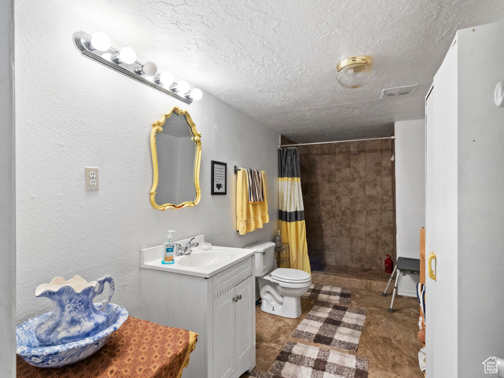 Bathroom with vanity, a textured ceiling, tile patterned flooring, and toilet