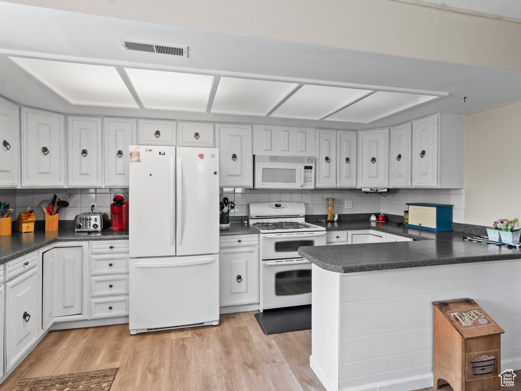 Kitchen with white cabinetry, tasteful backsplash, and white appliances