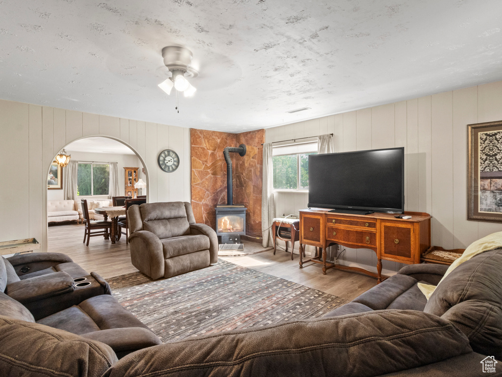 Living room featuring light hardwood / wood-style floors, a wood stove, and ceiling fan