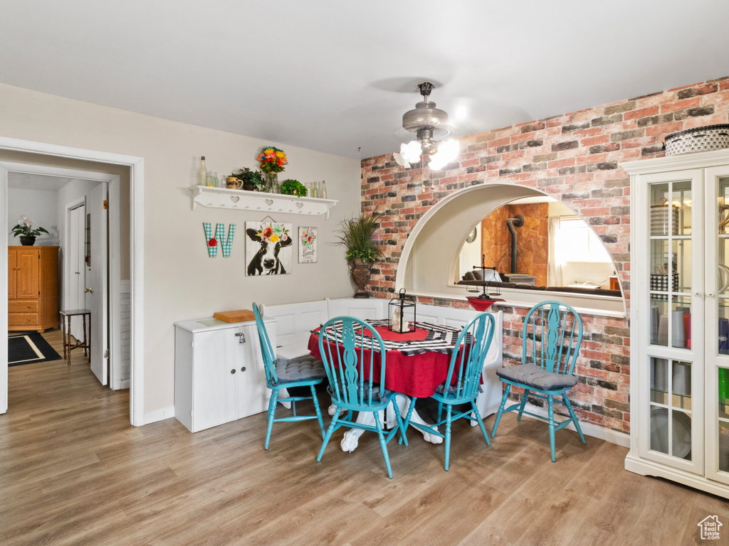 Dining room with ceiling fan, brick wall, and light hardwood / wood-style flooring