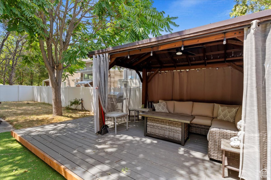 Wooden terrace featuring ceiling fan, a gazebo, and an outdoor hangout area