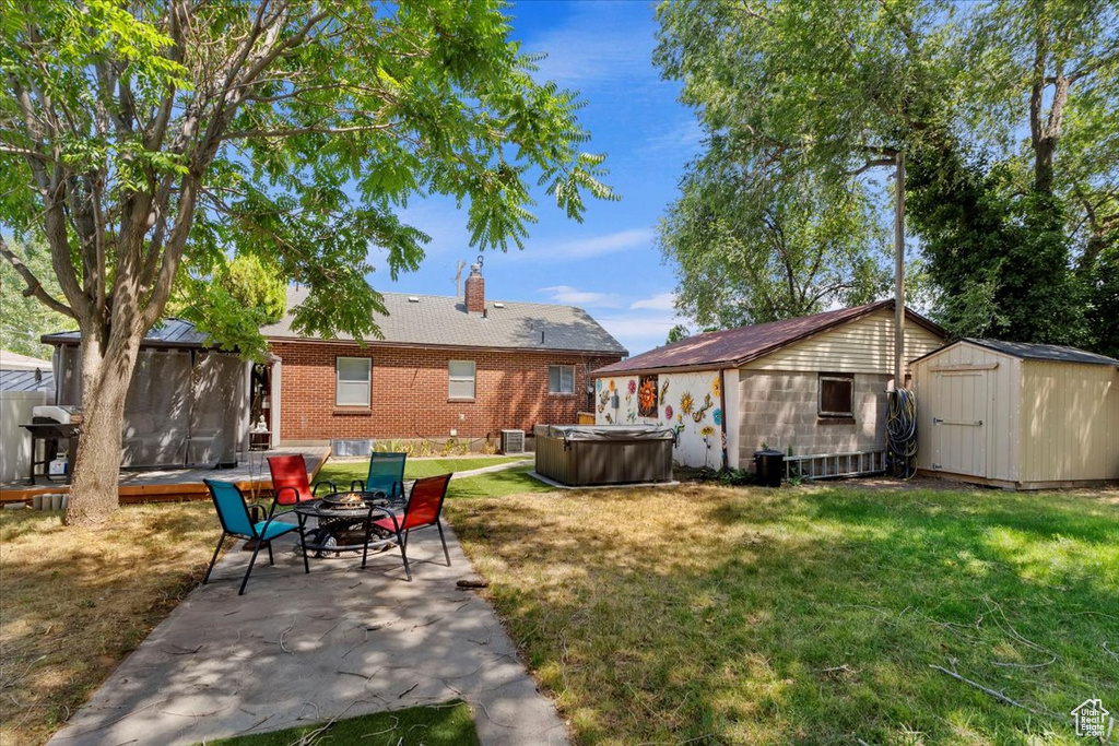 Back of house featuring a shed, a lawn, and a patio area