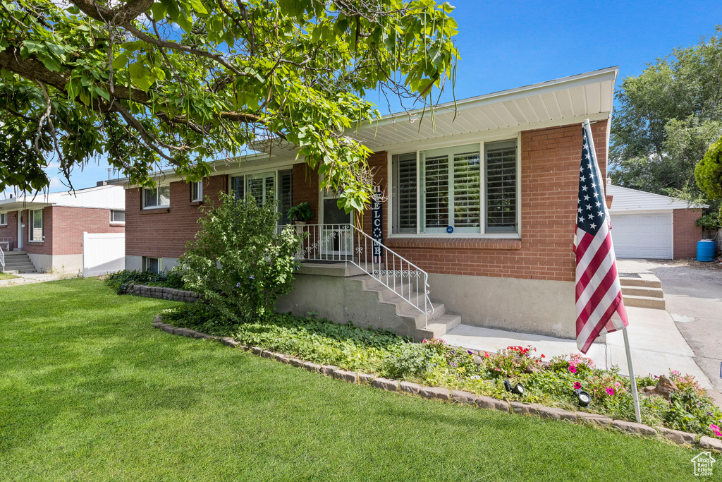 Ranch-style house with a garage, an outdoor structure, and a front lawn