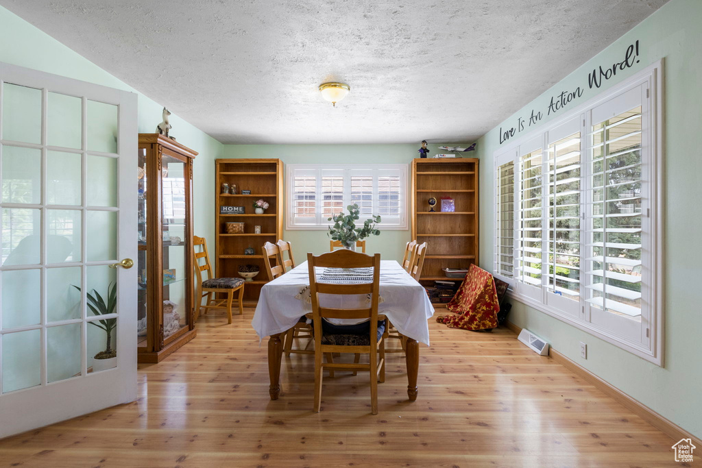 Dining room with a wealth of natural light, light wood-type flooring, and a textured ceiling