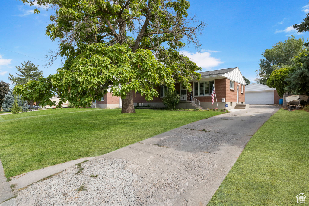 View of front of property with a garage, covered porch, an outdoor structure, and a front lawn