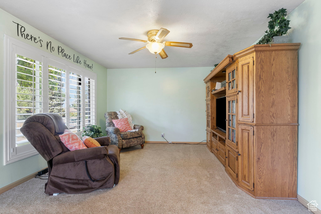 Living area with light colored carpet and ceiling fan