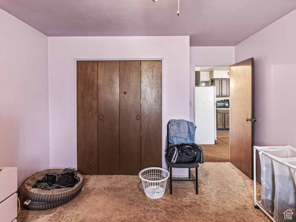 Carpeted bedroom featuring white fridge and a closet