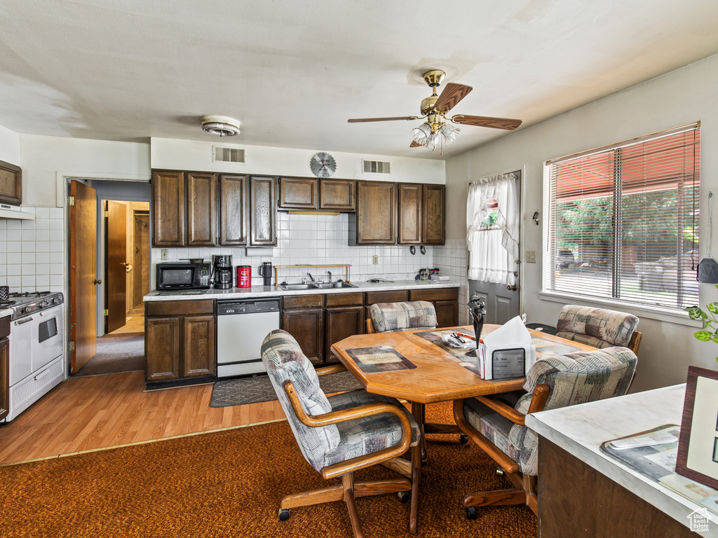 Kitchen featuring white appliances, dark brown cabinets, light hardwood / wood-style floors, decorative backsplash, and ceiling fan