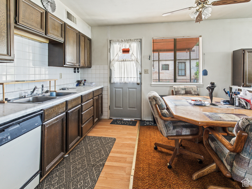 Kitchen featuring sink, decorative backsplash, light wood-type flooring, dishwasher, and ceiling fan