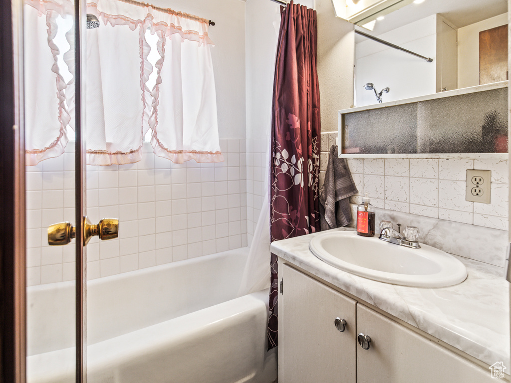 Bathroom with vanity, shower / bath combo, and backsplash