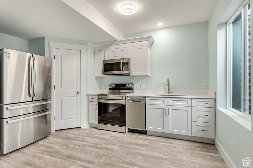 Kitchen featuring appliances with stainless steel finishes, a wealth of natural light, light wood-type flooring, and sink