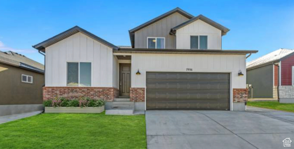 View of front of property with a garage and a front lawn