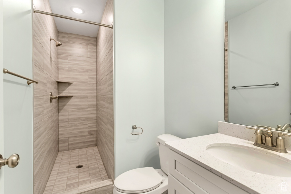 Bathroom featuring toilet, vanity, and a tile shower