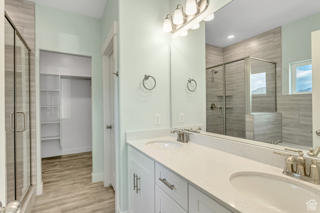 Bathroom featuring dual vanity, a shower with door, and wood-type flooring