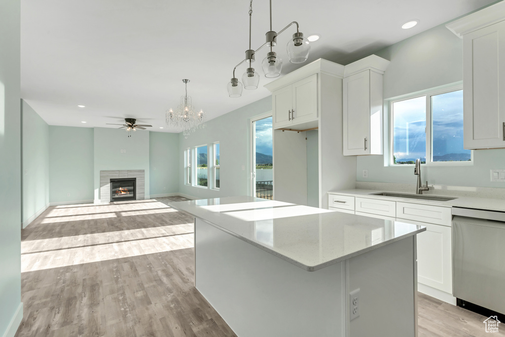 Kitchen with white cabinetry, light wood-type flooring, a center island, dishwasher, and sink