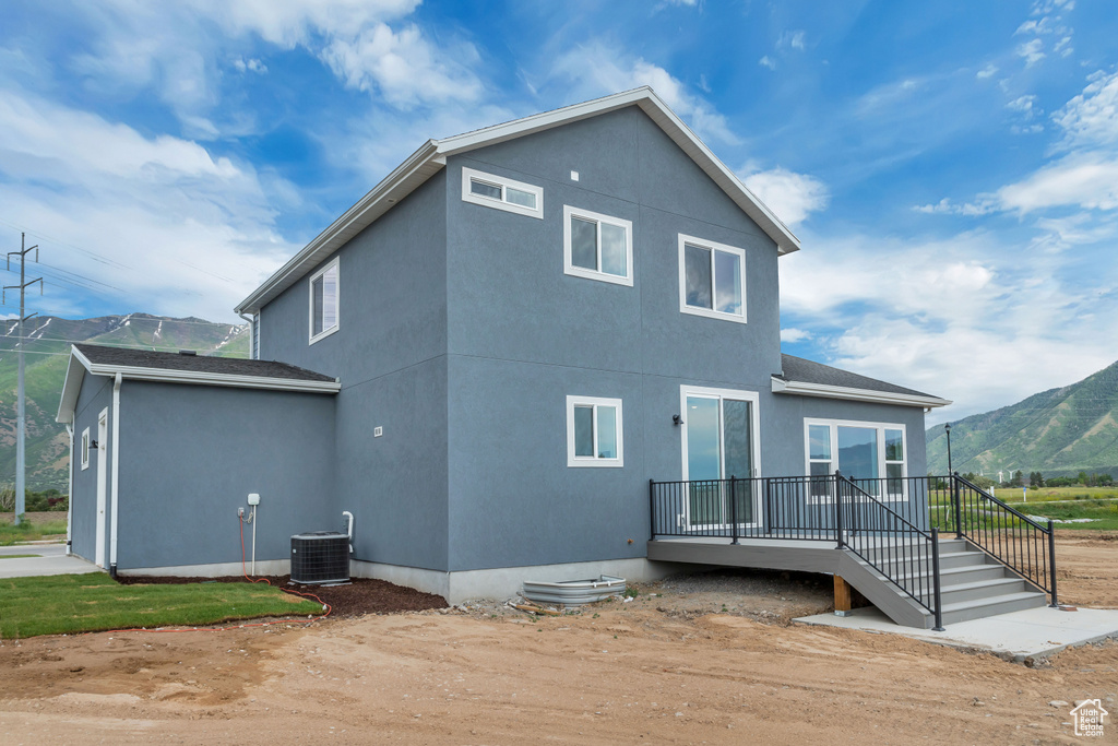 Back of property featuring a deck with mountain view and central AC unit