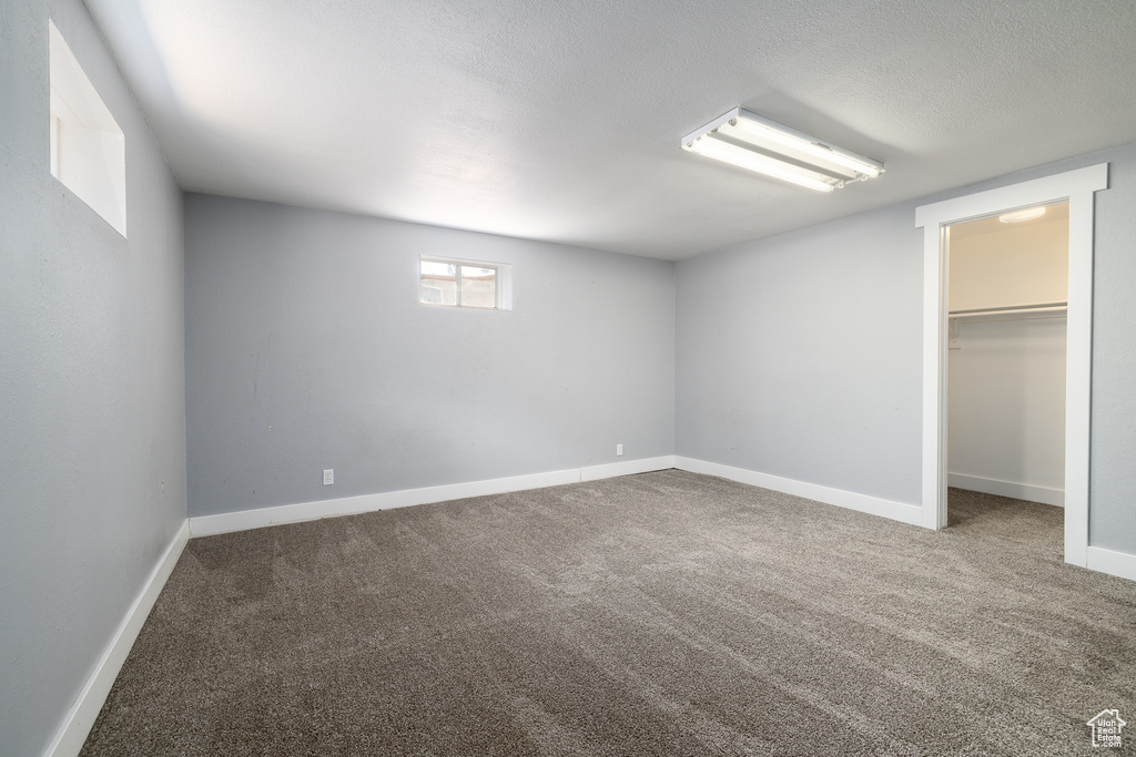 Unfurnished bedroom featuring a textured ceiling, a closet, carpet flooring, and a walk in closet