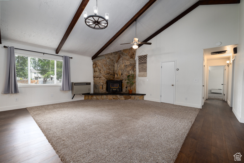 Unfurnished living room with a fireplace, dark hardwood / wood-style flooring, ceiling fan with notable chandelier, and beam ceiling