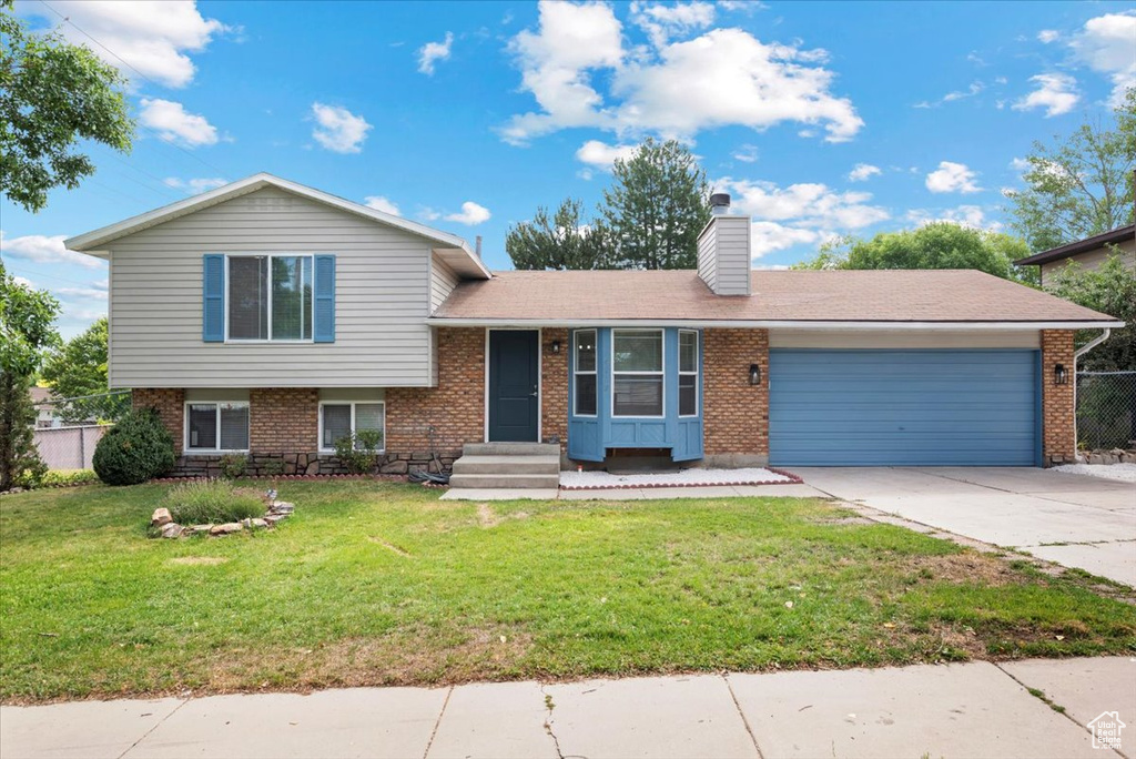 Split level home featuring a garage and a front lawn