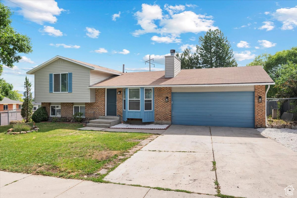 Split level home featuring a garage and a front lawn