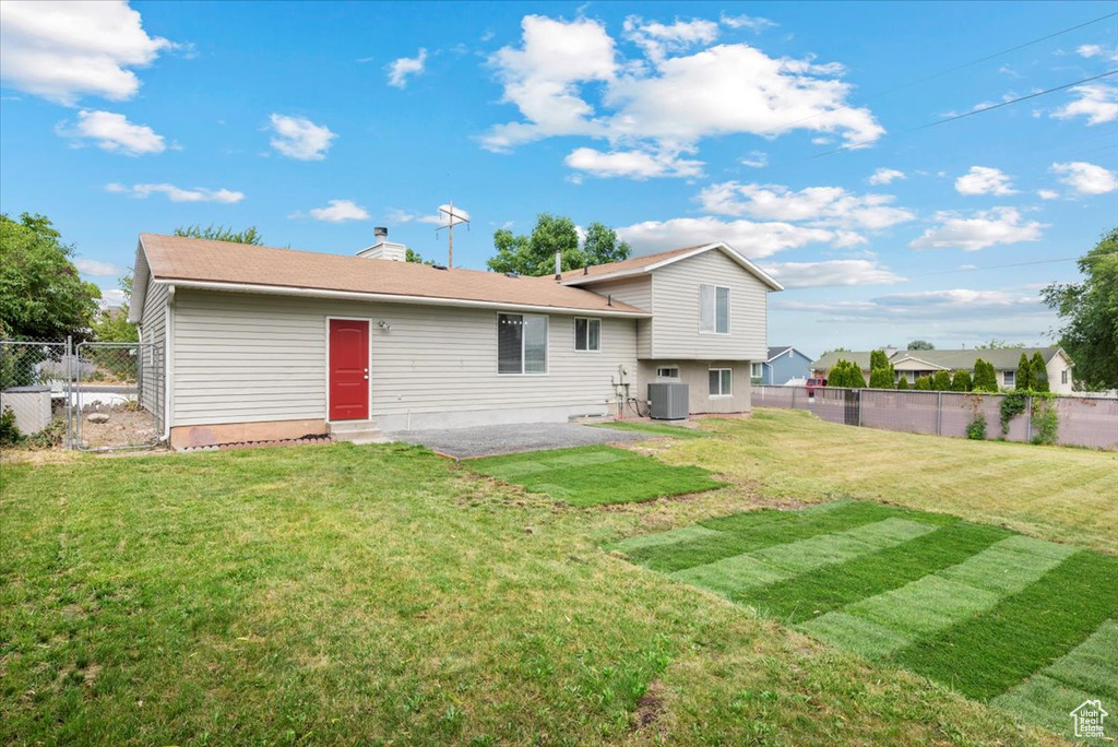 Rear view of property featuring central AC and a yard