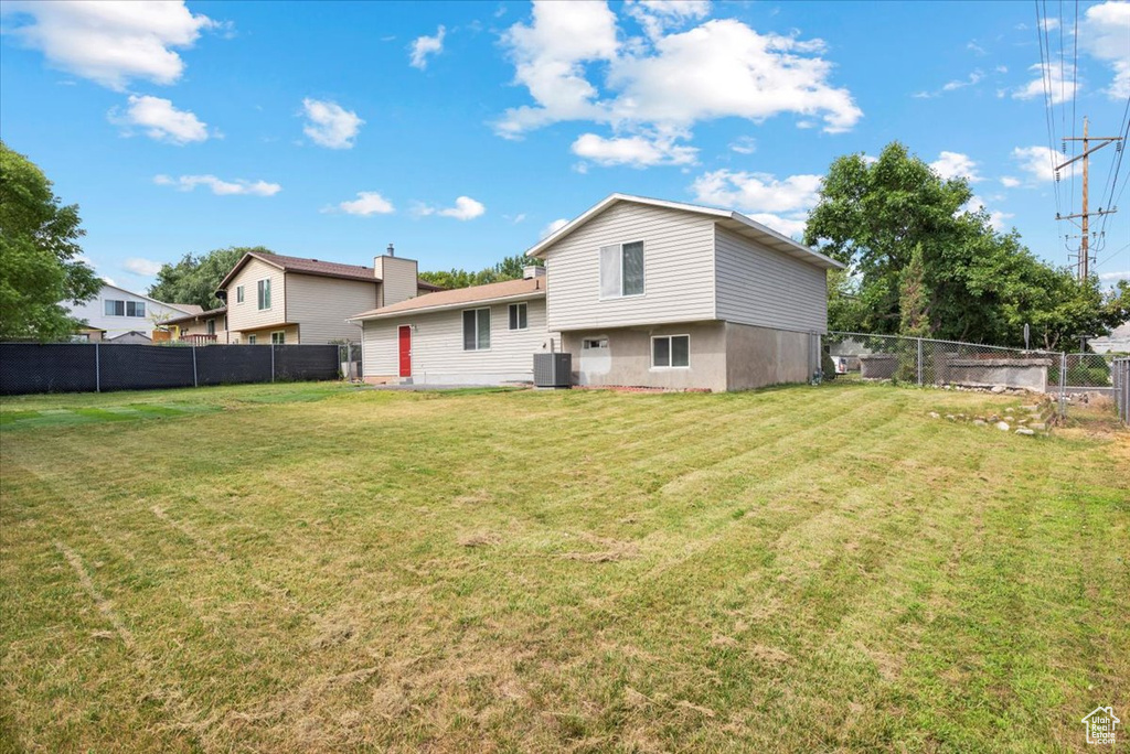 Back of property featuring a lawn and central AC unit