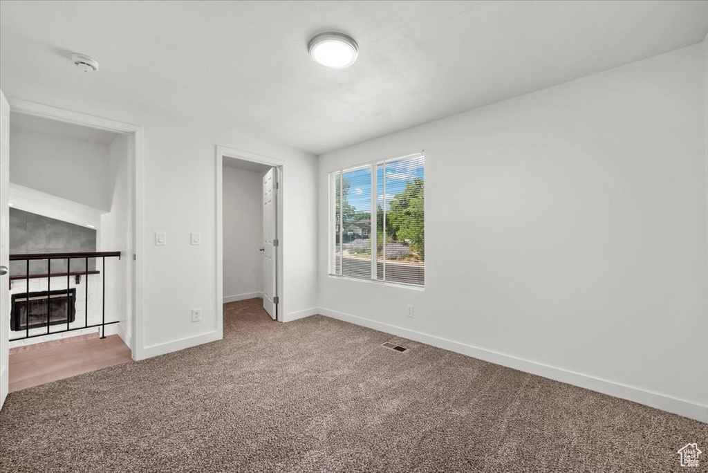 Unfurnished living room with a fireplace and light carpet