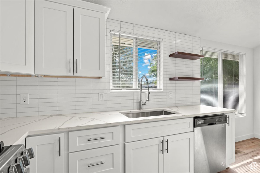 Kitchen with hardwood / wood-style floors, sink, backsplash, white cabinetry, and dishwasher