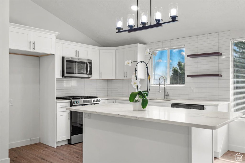 Kitchen featuring white cabinets, sink, appliances with stainless steel finishes, light hardwood / wood-style flooring, and lofted ceiling