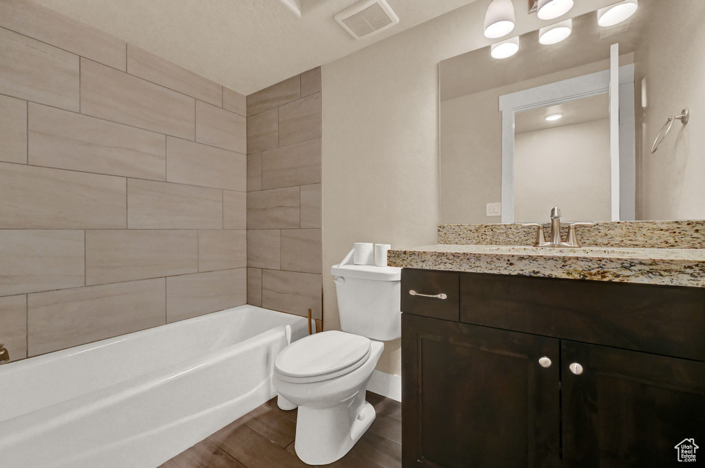 Full bathroom with vanity, tiled shower / bath, wood-type flooring, and toilet