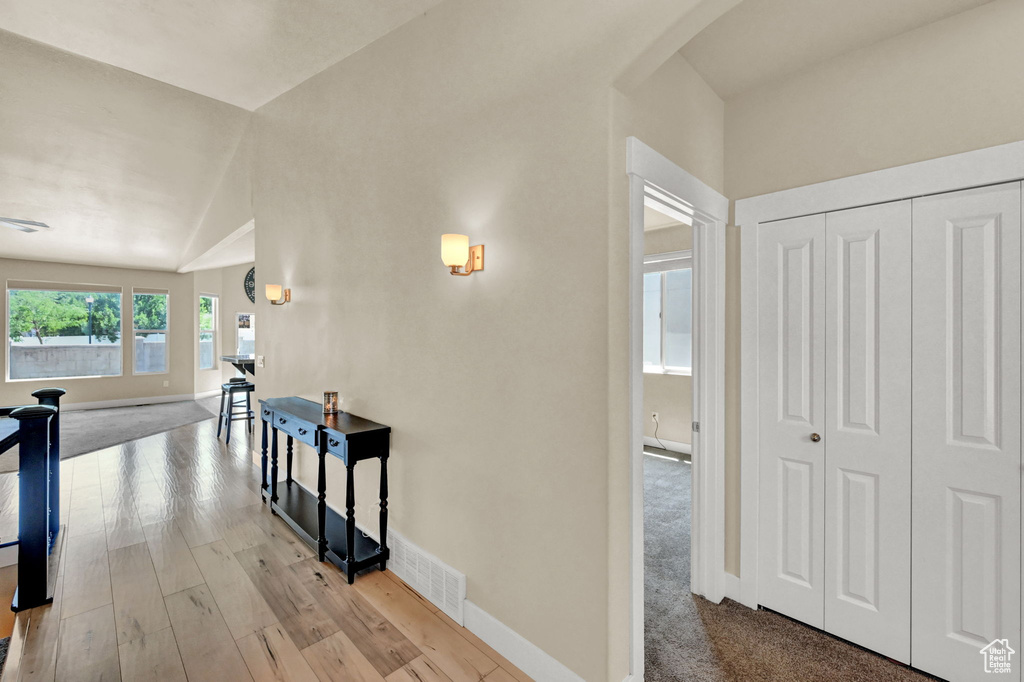 Corridor with light carpet and lofted ceiling