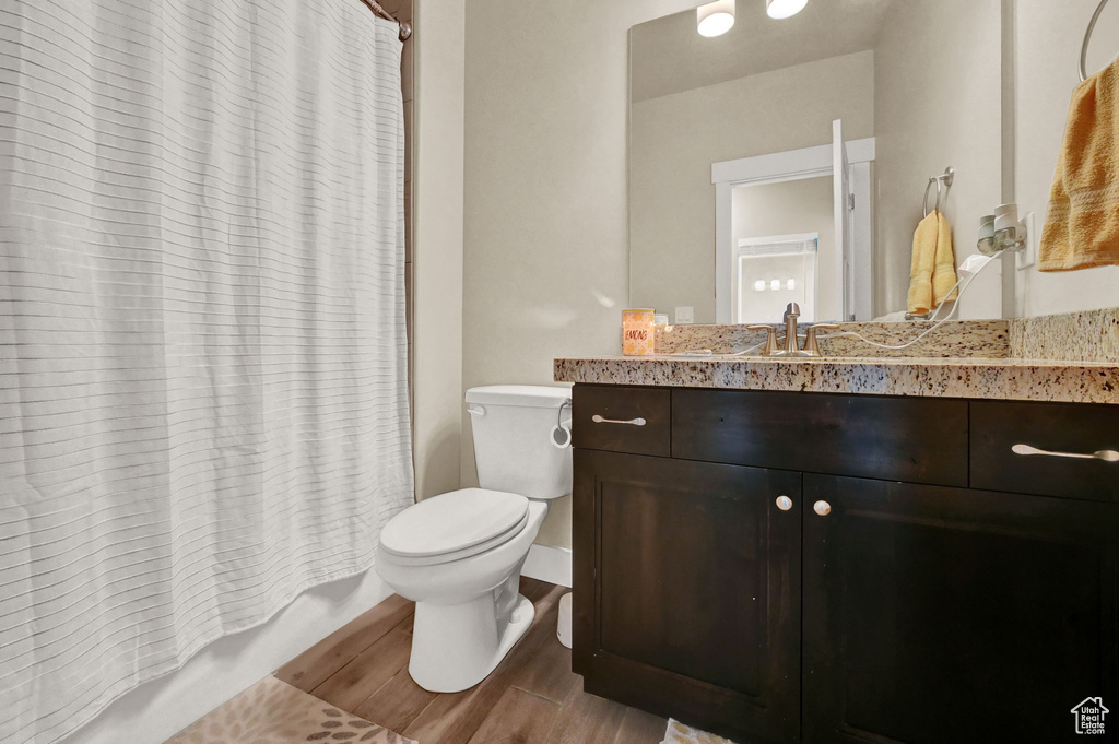 Full bathroom with hardwood / wood-style flooring, shower / bath combo, toilet, and vanity