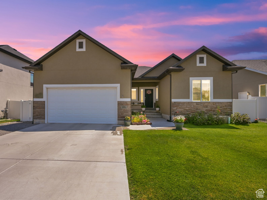 View of front of property featuring a garage and a lawn