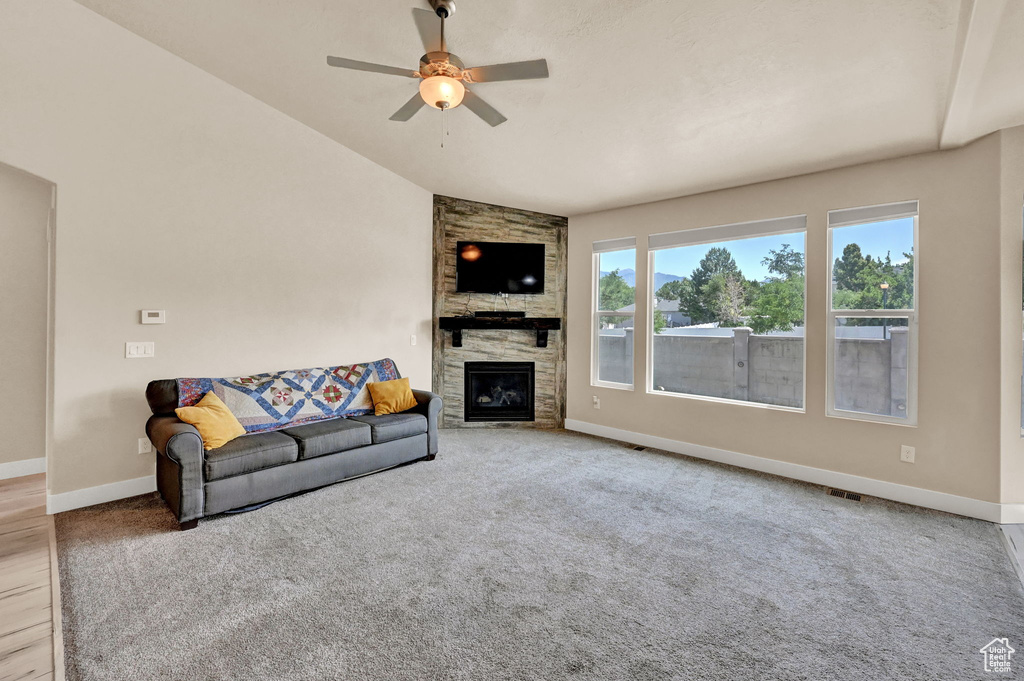 Living room with carpet floors, a fireplace, ceiling fan, and vaulted ceiling