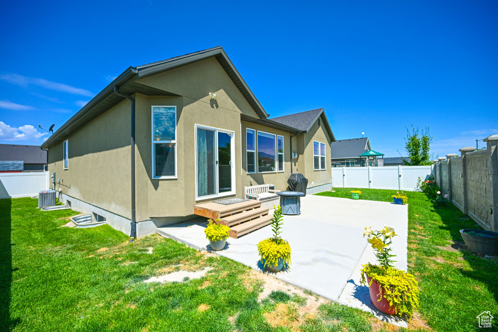 Back of house featuring a patio, a lawn, and central AC unit