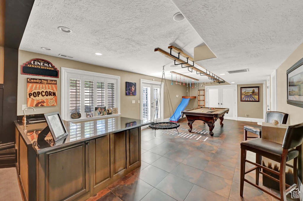 Playroom featuring dark tile patterned floors, billiards, and a textured ceiling